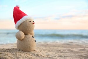 Snowman made of sand wearing a Santa hat on the California beach 