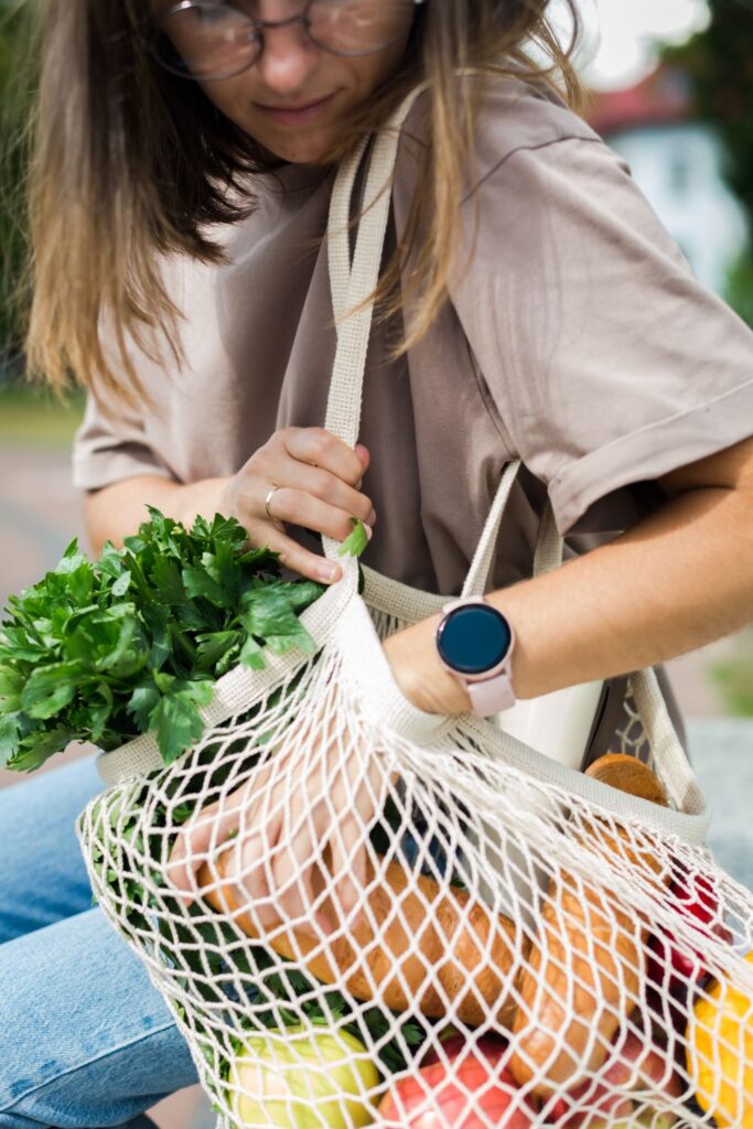 Person holding a reusable bag of vegetables while waiting for the local bus. 